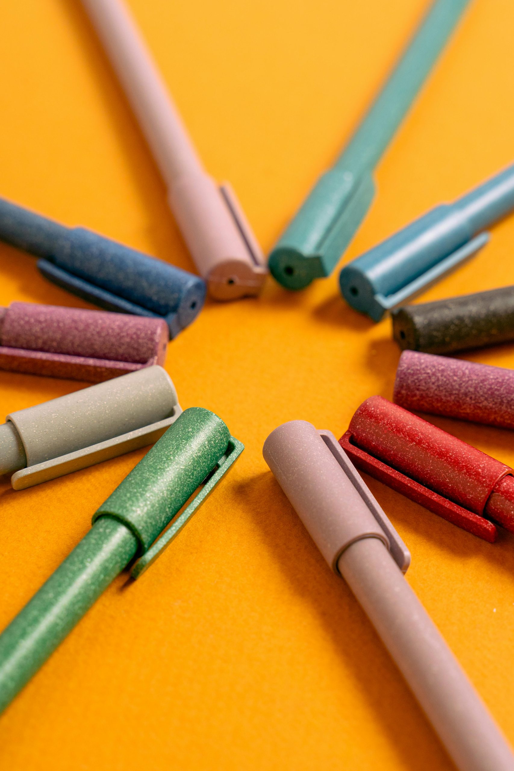 A close-up of colorful pens arranged on an orange surface, perfect for school or office themes.